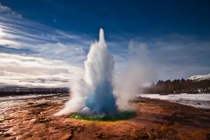 erupting strokkur geyser on a sunny day in iceland