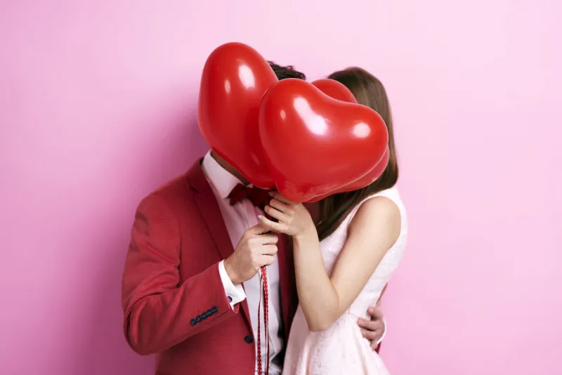 couple kissing behind balloons