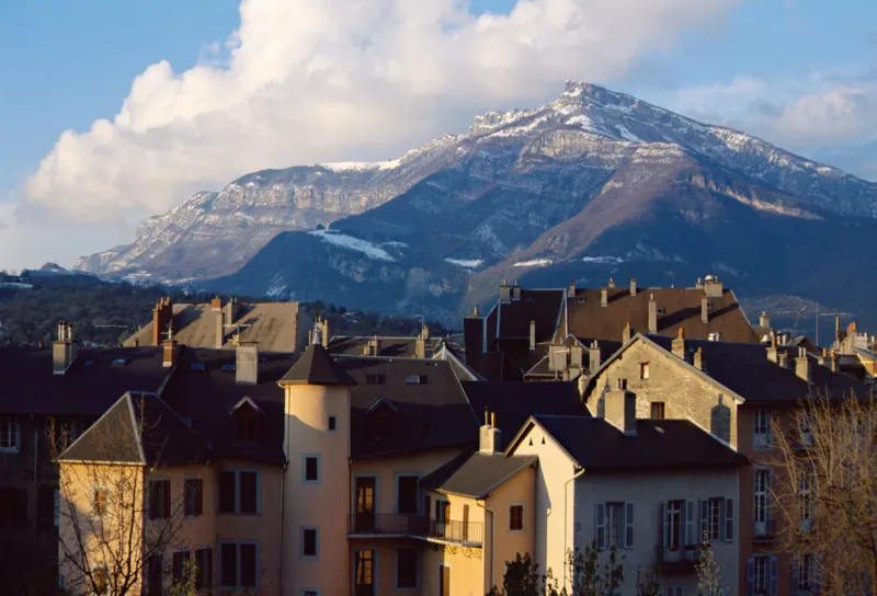 view of roofs of the old city of chambery in savoy, france and snowed mountain of nivolet's cross in sunset light