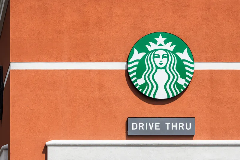gainesville, usa - april 27, 2018  sign logo closeup for starbucks coffee shop isolated on wall in florida and text for drive thru through for convenience