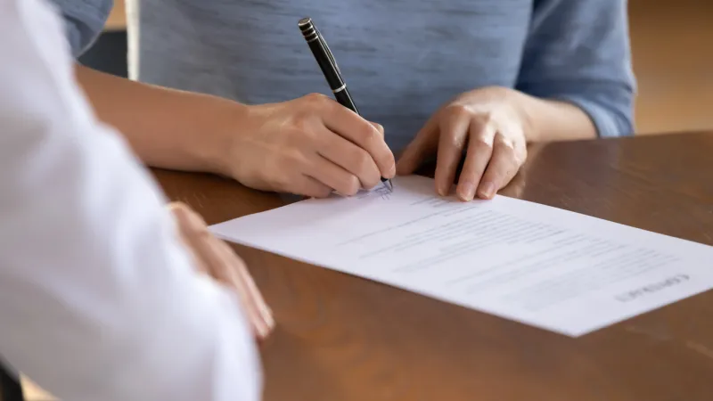 close up young woman signing medical insurance service contract with chosen family doctor at consultation meeting in clinic office satisfied patient putting signature on paper document in hospital