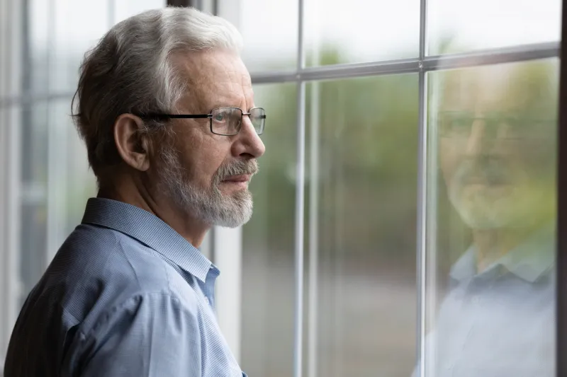 pensive elderly mature senior man in eyeglasses looking in distance out of window, thinking of personal problems lost in thoughts elderly middle aged grandfather suffering from loneliness, copy space