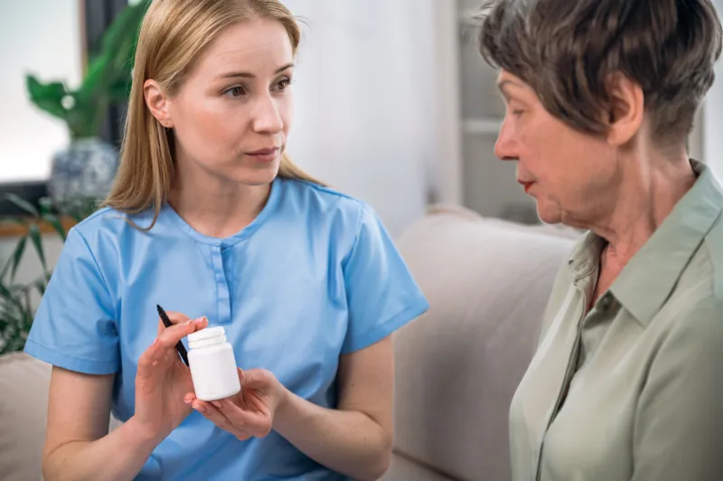 woman doctor consulting and prescribing medicines to senior female patient in hospital general practitioner holding white bottle with pills elderly healthcare concept