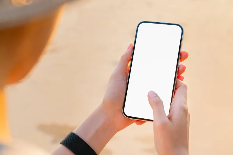 hand holding smartphone on the beach, mobile mockup of blank screen, take your screen to put on advertising summer vacation concept