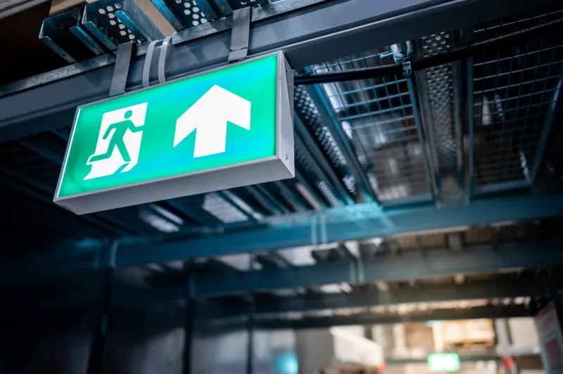 green emergency exit sign or fire exit sign showing the way to escape with arrow symbol