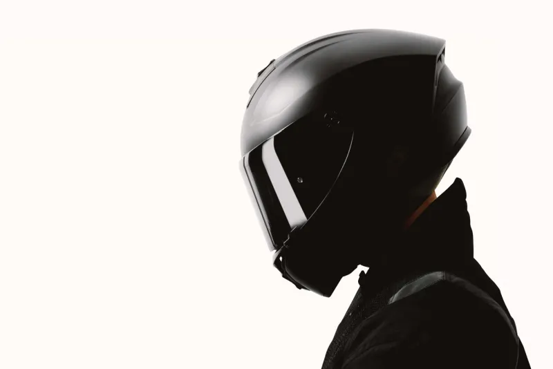 portrait of a motorcycle rider posing with a black helmet on a white background
