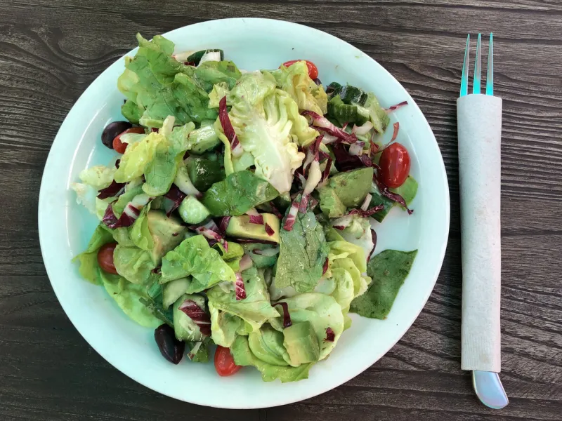healthy salad plate on a wooden table in the patio seating area top view