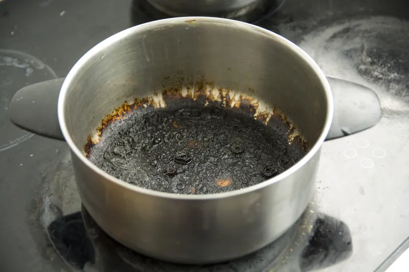 empty burnt pot with black bottom over the stoves