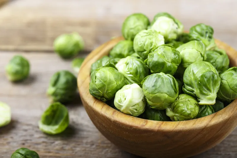 fresh organic brussels sprouts raw in a plate on wooden background space for text