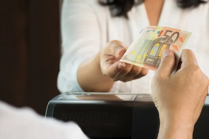 young man paying cash at retail shop customer and woman cashier in white dresses holding euro money