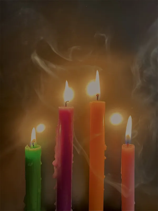 4 candles in 4 colors with a black background with smoke
