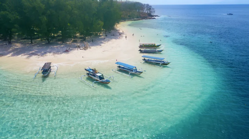 image of tourist ships anchored on the gili rengit beach at lombok, indonesia