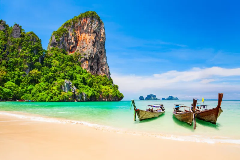 boats at the beauty beach with limestone cliff and crystal clear water in thailand