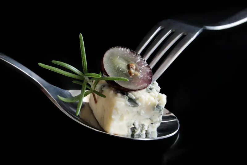 blue cheese with grape and rosemary on spoon