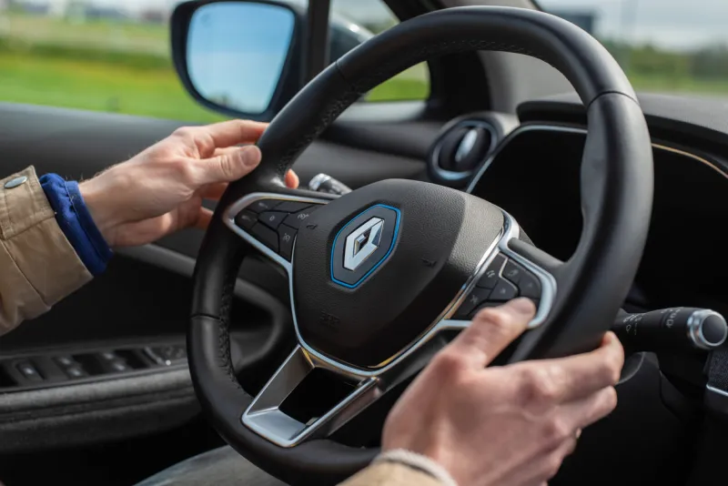 saku, estonia - may 20, 2021  new renault zoe 2021 electric car interior man hand holding the steering wheel selective focus