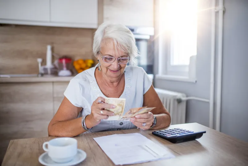 senior woman doing finances at home happy senior woman with calculator and bills counting euro money at home business, savings, annuity insurance, age and people concept