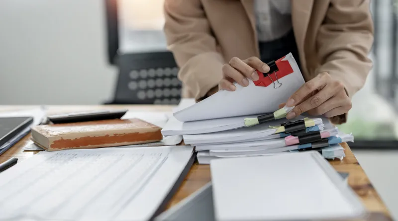 businesswoman hands working on stacks paper document files on her desk