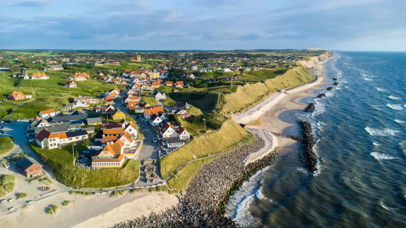 danish coastline with endless sand beach, water waves and the village lonstrup