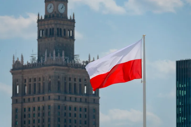 flag of poland waving at wind against beautiful blue sky and palace of culture and science