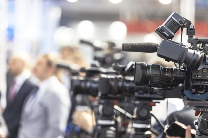 press or news conference filming media event with a video camera