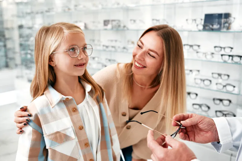 mature ophthalmologist demonstrates optical glasses to a child girl and her mother while visiting a professional store with various glasses eyesight correction healthcare, sight problem