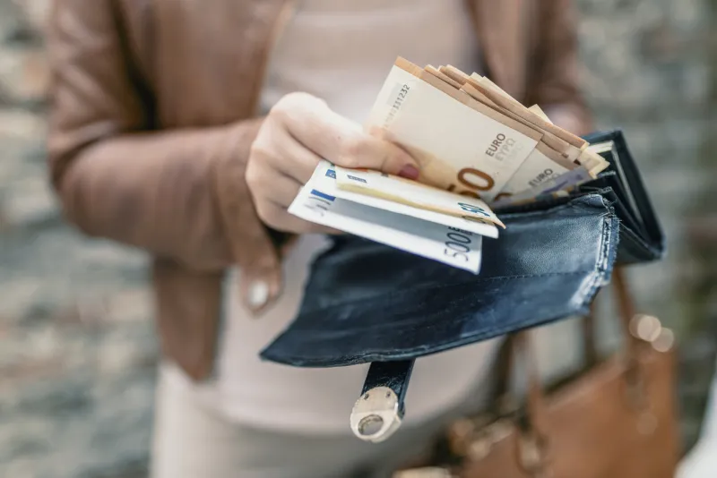 woman holding in hands wallet with euro money city girl is taking out money from wallet
