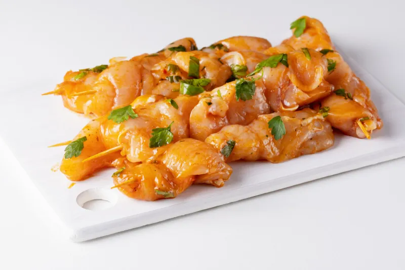 raw chicken skewers in marinade with spices on a white board raw marinated and spicy chicken skewers chicken meat close up raw meat in marinade