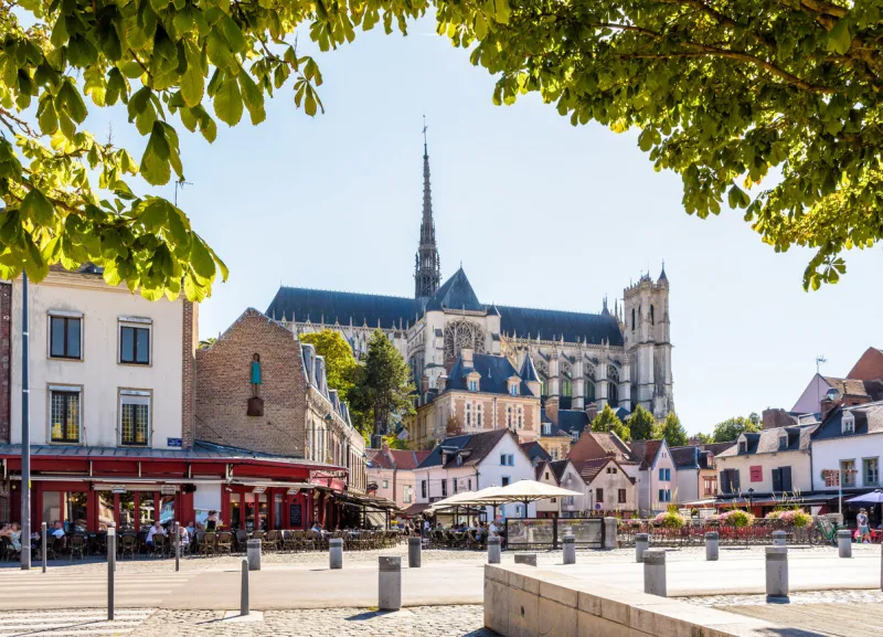 amiens, france - august 13, 2022  general view of notre-dame d'amiens cathedral overlooking the don square lined with historic townhouses, sidewalk cafes and restaurants on a sunny summer day
