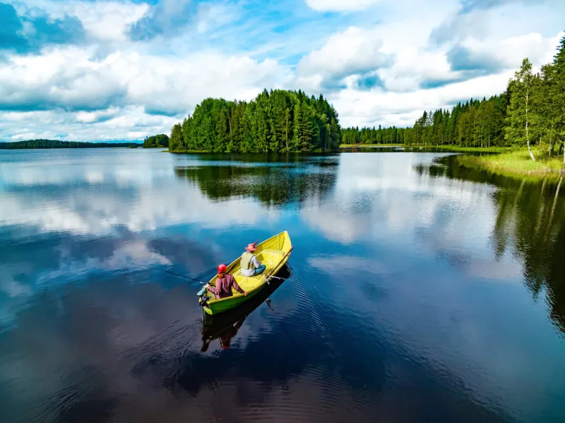 aerial view of fishing boat with young woman and man in blue summer lake in finland