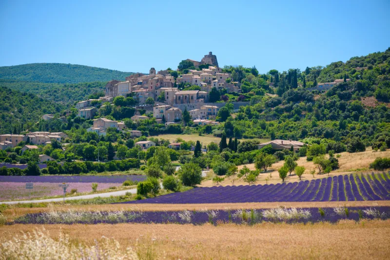 city of saint-saturnin-les-apt on the hill with lavender fields in valley on summer day provence, france