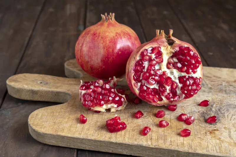 pomegranates on the cutting board on the old wooden kitchen table vegan and vegetarian food healthy eating ecological agriculture concept