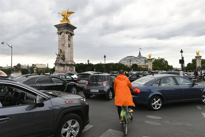 paris, france-07 05 2023 cyclist entering the alexandre iii bridge in the middle of a stream of cars, paris, france