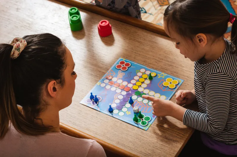 mother and daughter playing board game at home