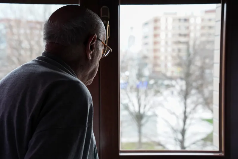 caucasian senior looking at the window loneliness in elderly