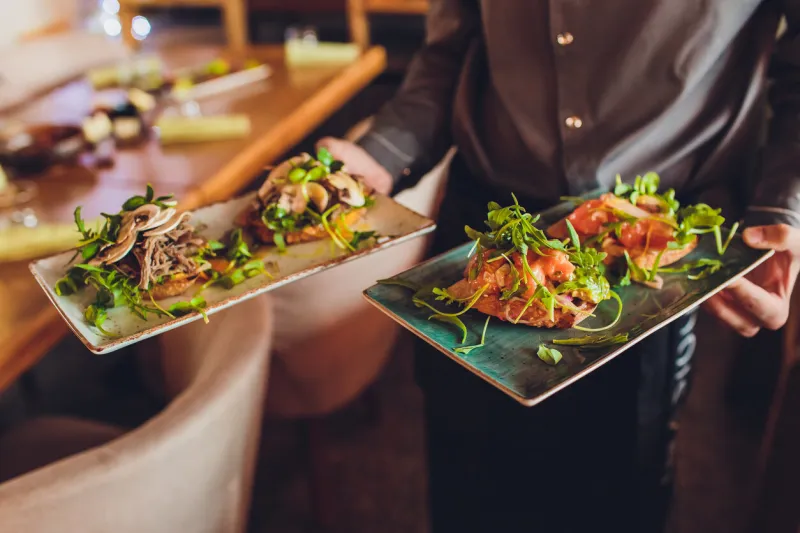 two meat plate with salad leaves and summer salad in waiter's hand