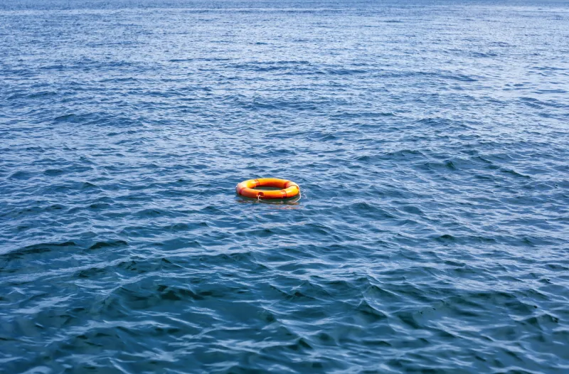 orange life buoy floating in vast expanse of sea red lifebuoy float on ocean waves lifeguard equipment with rope swimming in lake concept of help, rescue, drowning, saving, surviving, protection