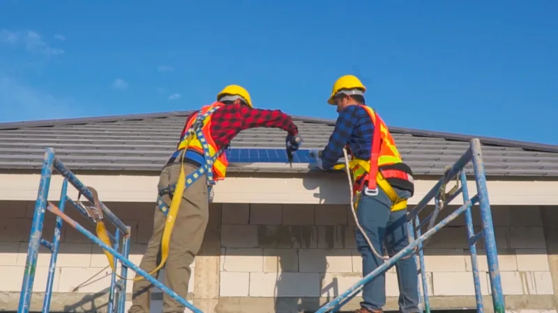 two technicians installing solar panels on the roof of a house