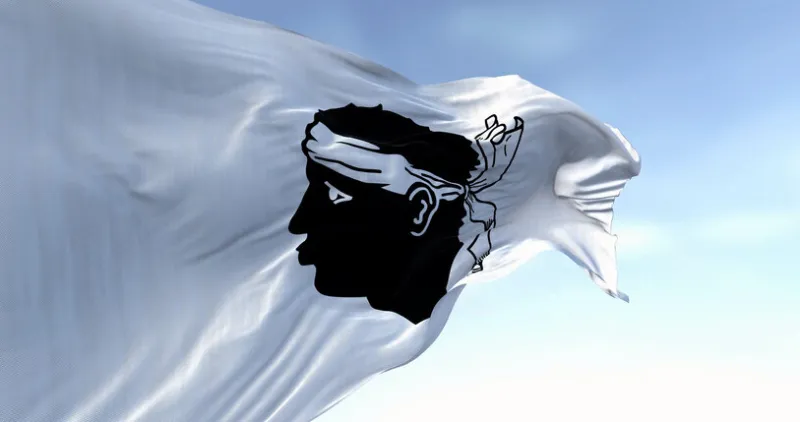 flag of corsica waving in the wind on a clear day black moor's head with a white bandana on a white field french region 3d illustration render selective focus
