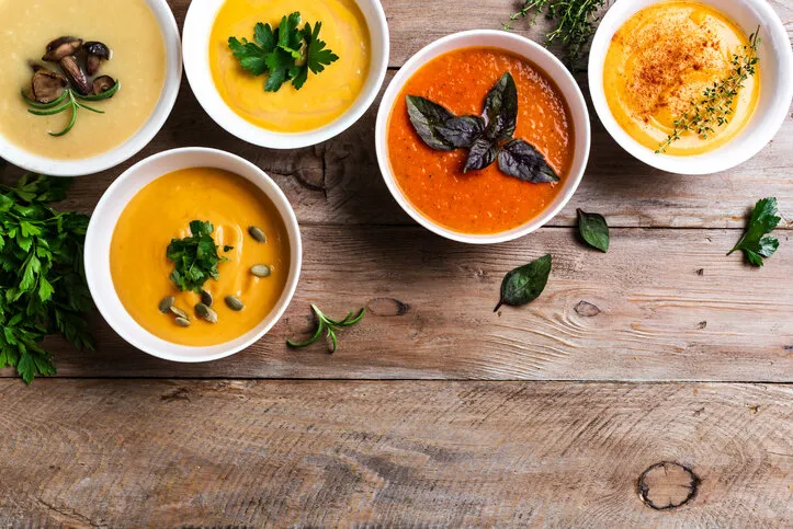 autumn soups set of various seasonal vegetable soups and organic ingredients on wooden background, top view, copy space homemade colourful seasonal vegan soups