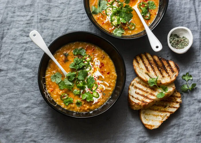 curried red lentil tomato and coconut soup - delicious vegetarian food on grey background, top view flat lay served healthy lunch