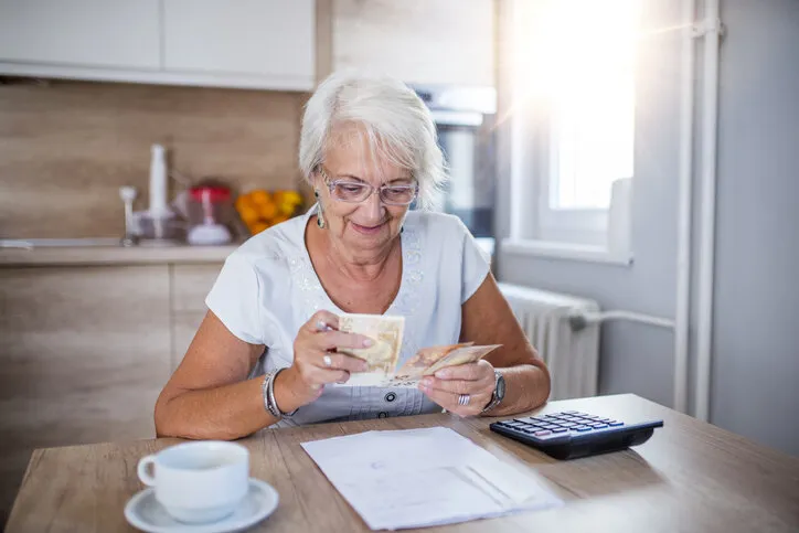 senior woman doing finances at home happy senior woman with calculator and bills counting euro money at home business, savings, annuity insurance, age and people concept