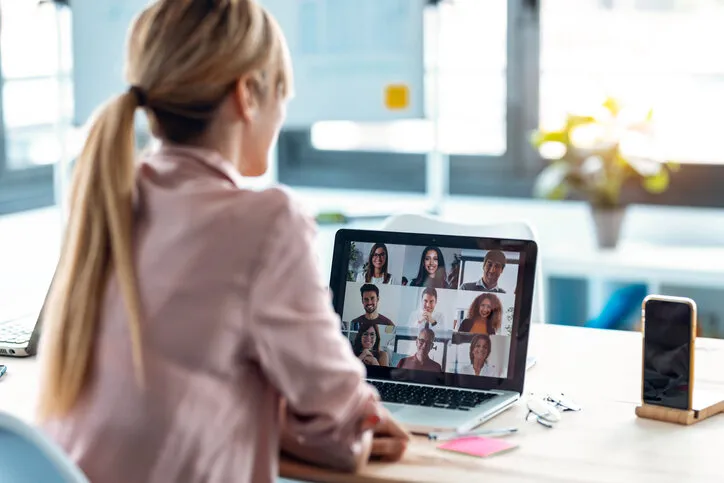 back view of female employee speaking on video call with diverse colleagues on online briefing with laptop at home