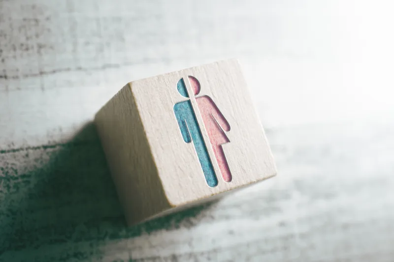 gender signs for male and female cut in half on a wooden block on a table
