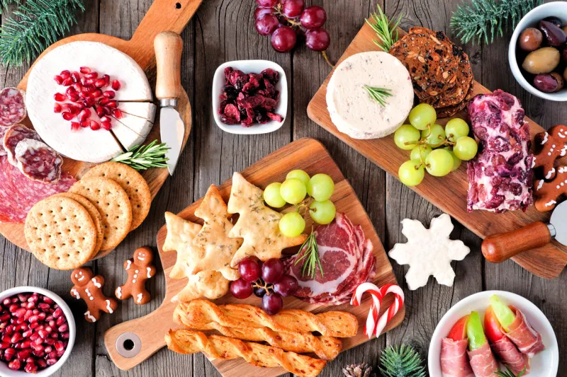 christmas theme charcuterie table scene against a dark wood background assortment of cheese and meat appetizers top view