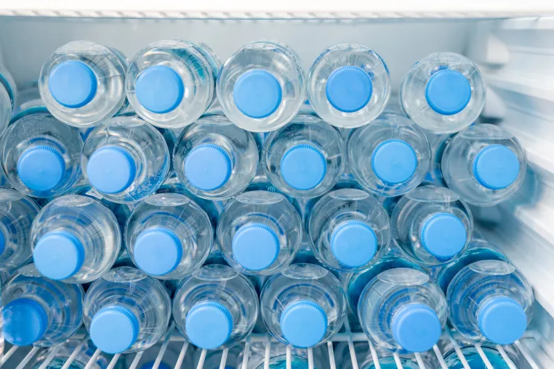 rows of many transparent plastic bottles with drinking water supply in white refrigerator mineral water stack storage in fridge to drink on hot summer day healthcare and dehydration prevention