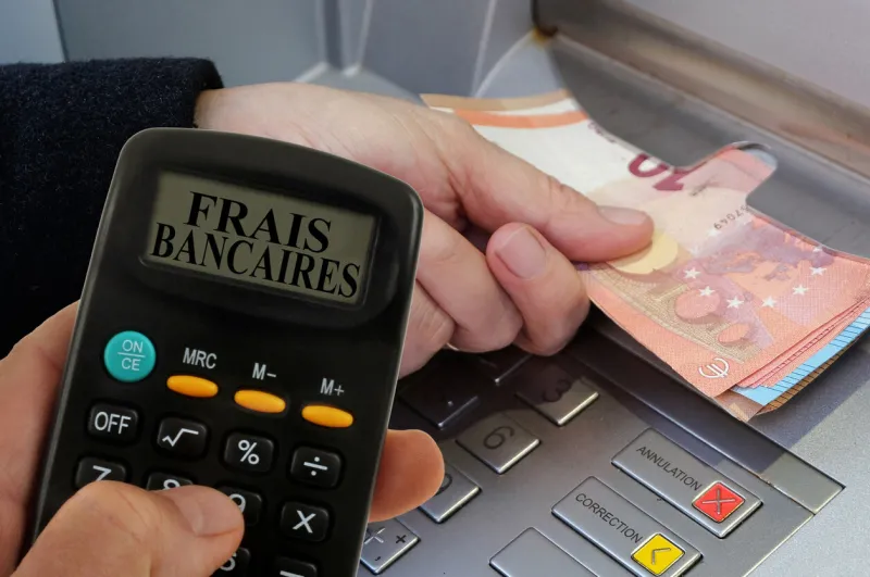 bank charges concept with a calculator and someone withdrawing euro banknotes from an atm in the background