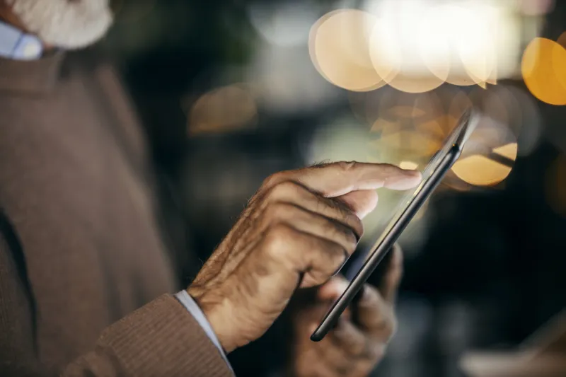 cropped picture of senior man's hand scrolling on pad