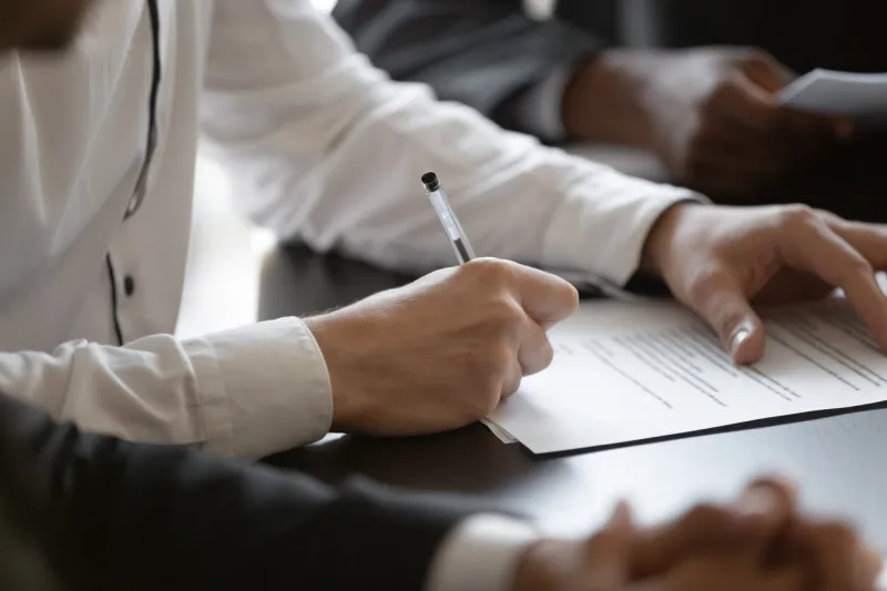 close up young male employee manager customer hands signing paper contract after checking millennial investor client put signature at business agreement between partners editor making corrections