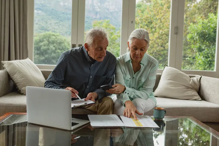 front view of active senior caucasian couple calculating bills in living room at home