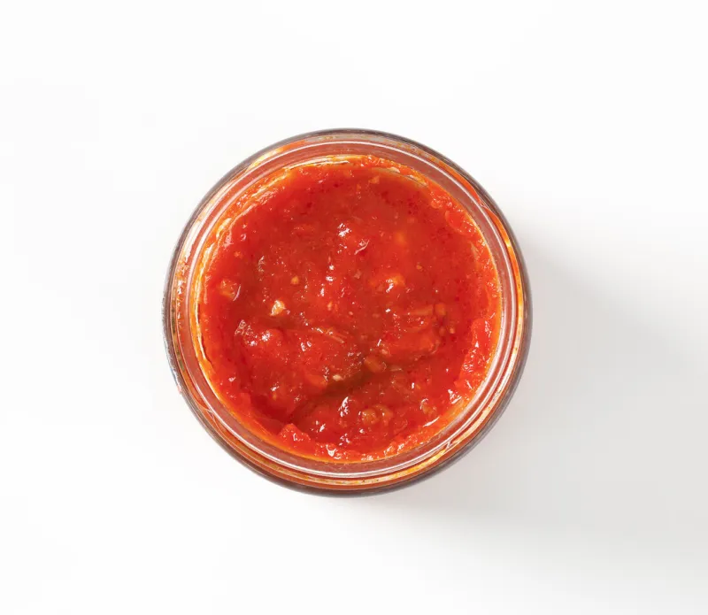 jar of tomato based pesto sauce on white background
